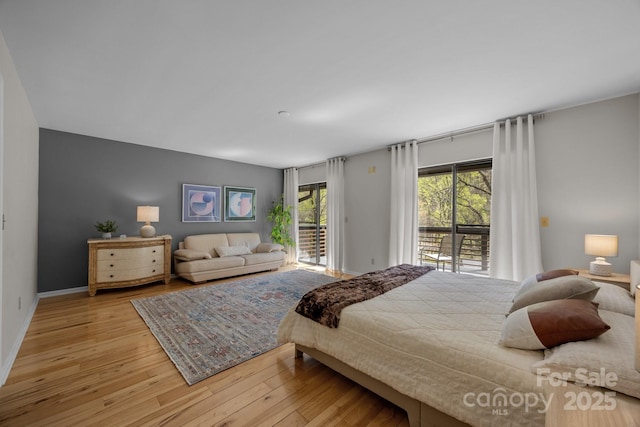 bedroom with baseboards, access to exterior, and hardwood / wood-style flooring