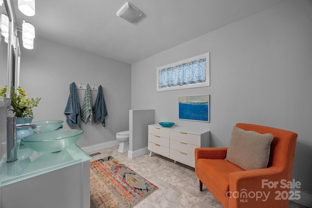 full bathroom with a sink, double vanity, toilet, visible vents, and baseboards