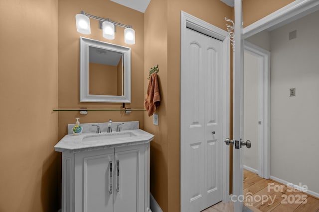 bathroom featuring baseboards, wood finished floors, and vanity