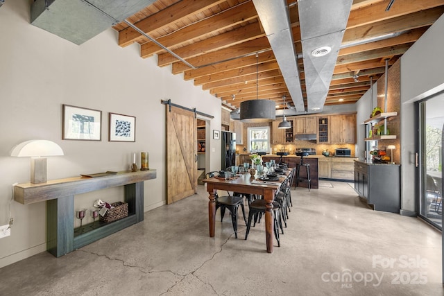dining area featuring a barn door, visible vents, baseboards, and finished concrete floors