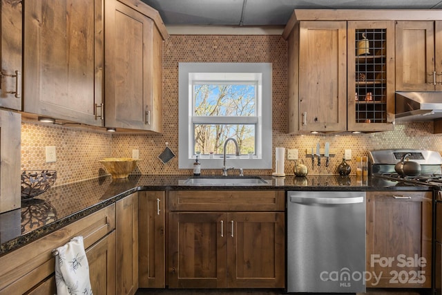 kitchen featuring dark stone counters, a sink, extractor fan, stainless steel appliances, and backsplash