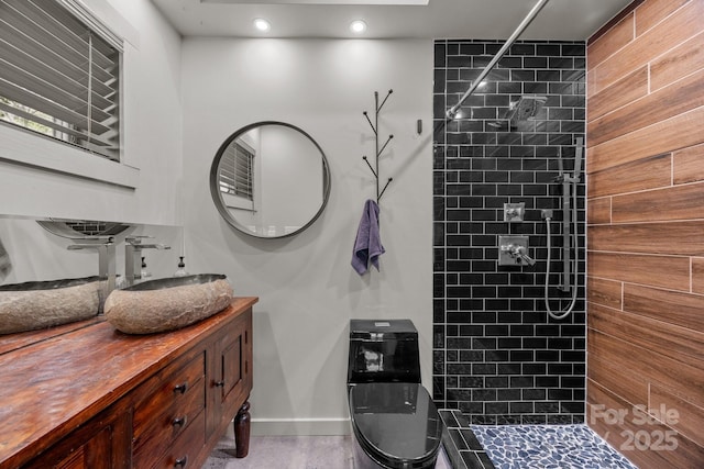 bathroom with recessed lighting, vanity, baseboards, and tiled shower