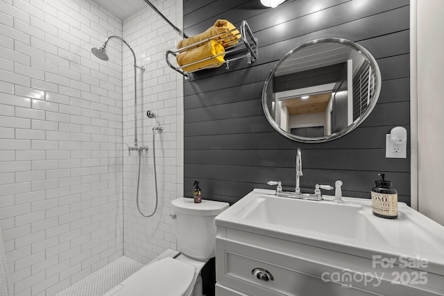 full bathroom with toilet, vanity, and a tile shower