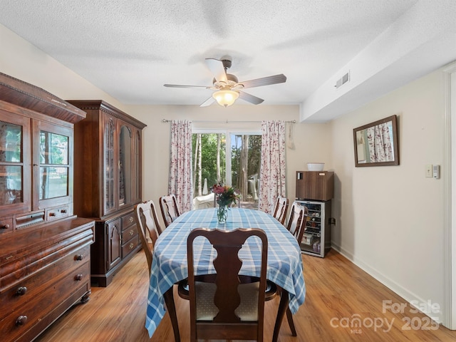 2248 Lawton Bluff Rd, Charlotte, NC 28226 - dining space with light wood finished floors, ceiling fan, wine cooler, and a textured ceiling