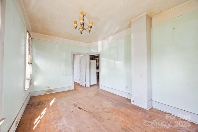 unfurnished room with baseboards, wood finished floors, a chandelier, and cooling unit