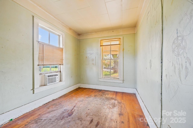 unfurnished room featuring cooling unit, wood-type flooring, and baseboards