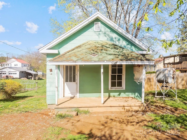 rear view of house with a porch, fence, and a yard