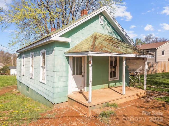 rear view of property with fence, a chimney, and covered porch