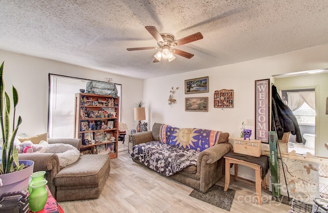 living room featuring a ceiling fan, a textured ceiling, and light wood-type flooring