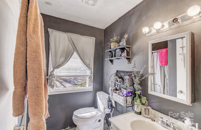 full bathroom featuring toilet, curtained shower, vanity, a textured ceiling, and visible vents