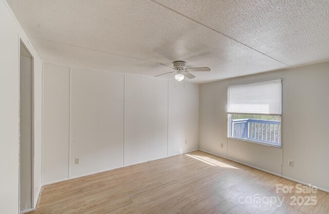 empty room featuring a textured ceiling, ceiling fan, and wood finished floors
