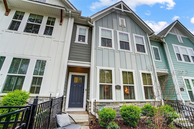 townhome / multi-family property with fence, stone siding, and board and batten siding