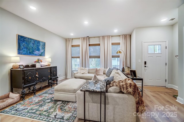 living room featuring baseboards, visible vents, wood finished floors, and recessed lighting