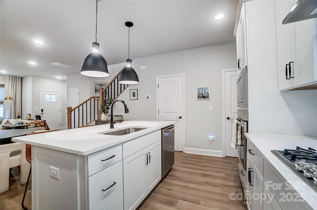 kitchen featuring a sink, light wood finished floors, white cabinetry, appliances with stainless steel finishes, and a kitchen bar