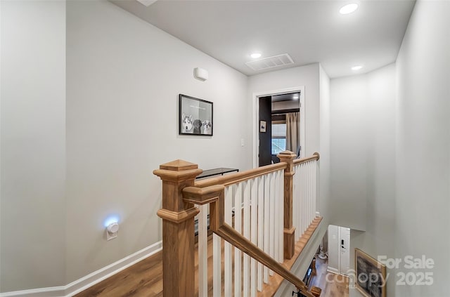 corridor with an upstairs landing, recessed lighting, baseboards, visible vents, and wood finished floors