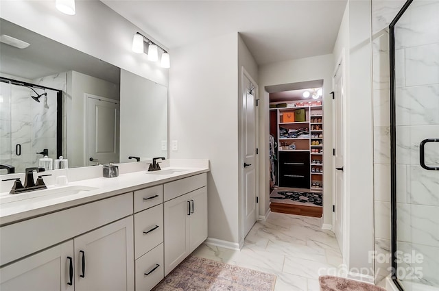 bathroom with marble finish floor, a sink, a stall shower, and double vanity