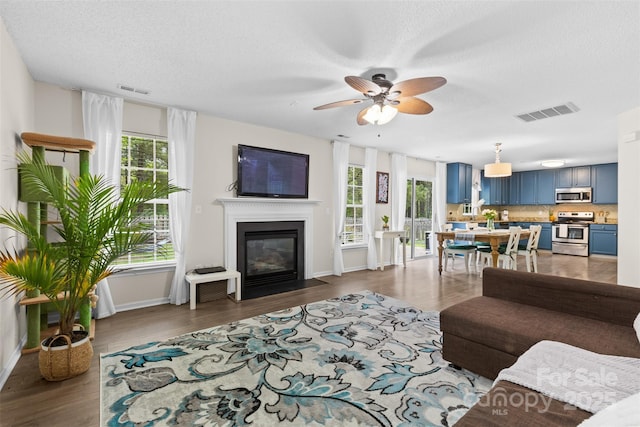 512 Red Oak Ct, Tega Cay, SC 29708 - living room with a fireplace with flush hearth, a textured ceiling, visible vents, ceiling fan, and dark wood-type flooring