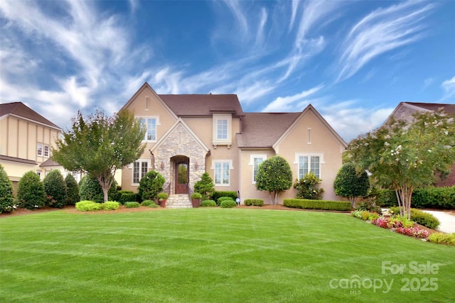 tudor house with stucco siding, a front lawn, and stone siding