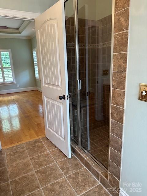 full bathroom with wood finished floors, a shower stall, baseboards, a raised ceiling, and crown molding