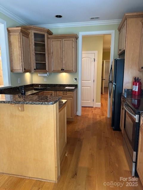 kitchen featuring dark stone counters, stainless steel electric range, light wood-type flooring, visible vents, and freestanding refrigerator