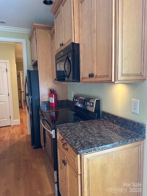 kitchen with dark stone countertops, visible vents, black appliances, light wood-type flooring, and ornamental molding