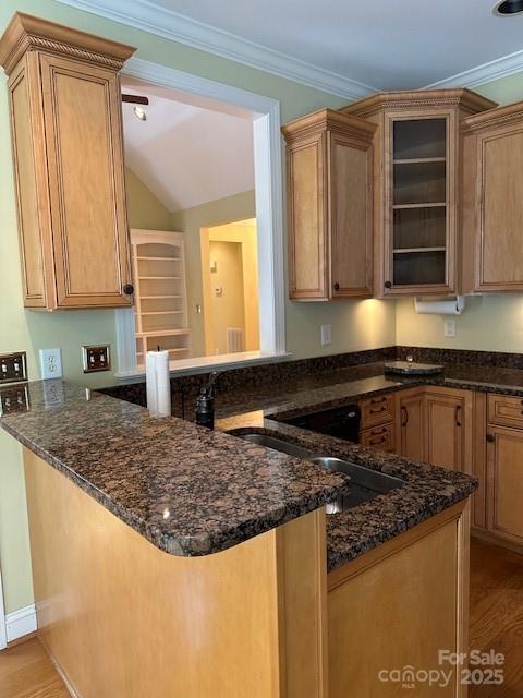 kitchen featuring dark stone counters, glass insert cabinets, a peninsula, and light wood-type flooring