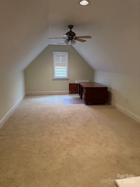 additional living space featuring ceiling fan, vaulted ceiling, light carpet, and baseboards