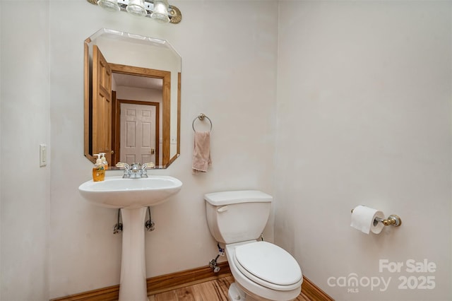 bathroom with toilet, wood finished floors, a sink, and baseboards