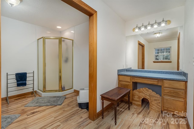 bathroom with a stall shower, wood finished floors, vanity, and baseboards