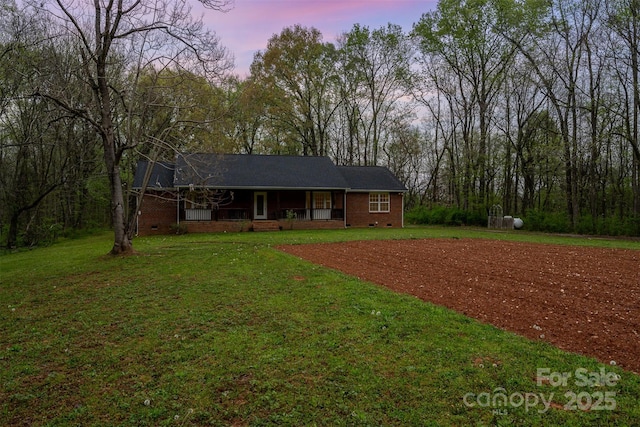 ranch-style home featuring a front yard, brick siding, covered porch, and crawl space