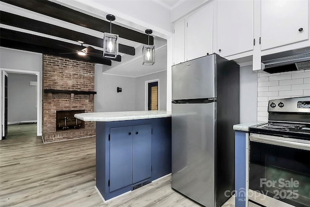 kitchen with light countertops, range hood, a brick fireplace, blue cabinetry, and stainless steel appliances