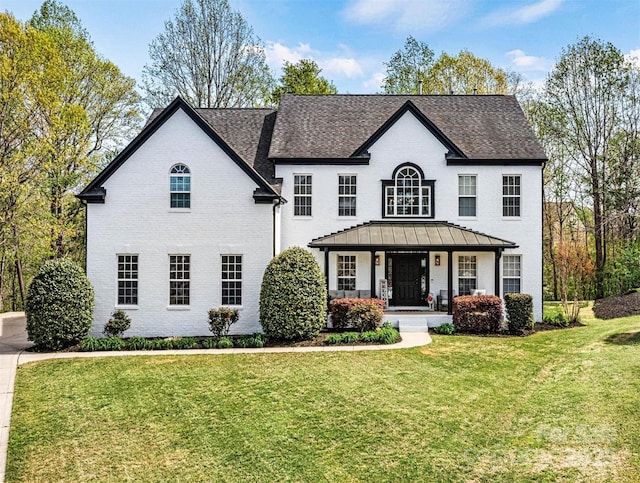 traditional home featuring brick siding, a porch, and a front lawn