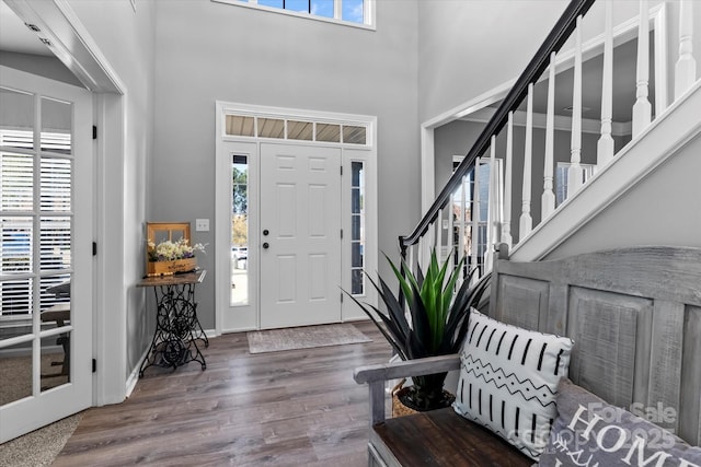 foyer entrance with wood finished floors, a high ceiling, plenty of natural light, and stairway