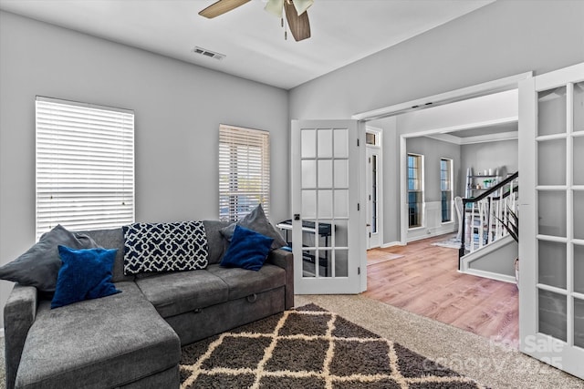 living room featuring a ceiling fan, stairs, wood finished floors, french doors, and visible vents