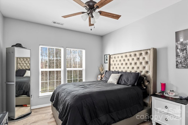 bedroom featuring light wood-type flooring, visible vents, a ceiling fan, and baseboards