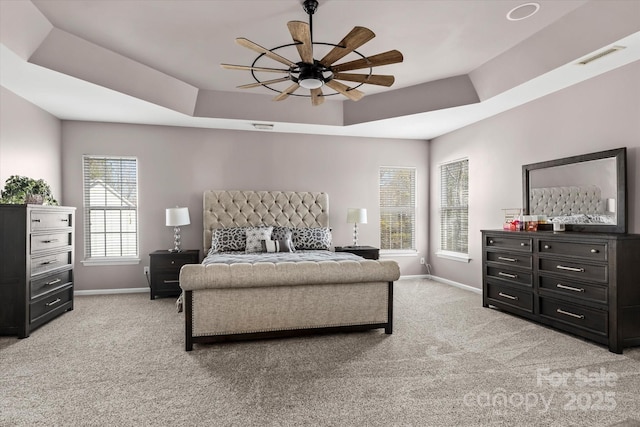 bedroom featuring a ceiling fan, light carpet, a raised ceiling, baseboards, and visible vents