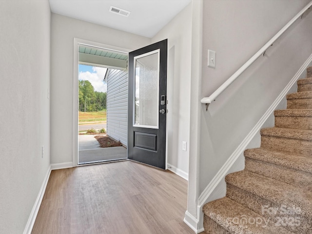foyer entrance featuring stairs, visible vents, wood finished floors, and baseboards