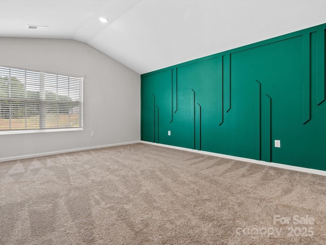unfurnished bedroom with carpet floors, vaulted ceiling, and visible vents