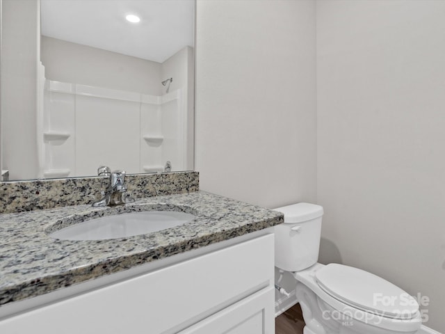 bathroom with toilet, vanity, wood finished floors, and walk in shower