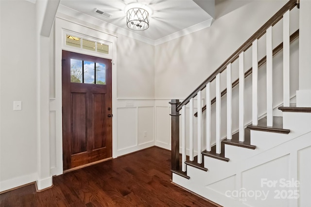entrance foyer featuring visible vents, stairs, a decorative wall, a wainscoted wall, and dark wood finished floors