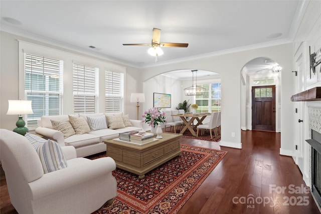 living area featuring visible vents, arched walkways, dark wood finished floors, and a ceiling fan