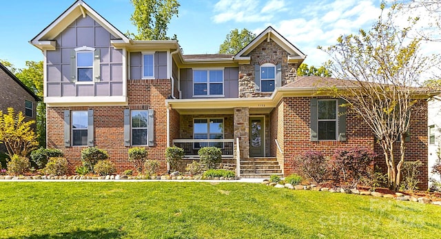 view of front of home with brick siding, a front lawn, stone siding, a porch, and board and batten siding