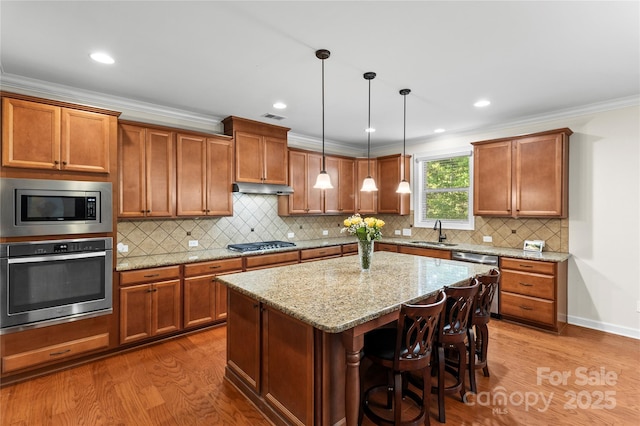kitchen featuring appliances with stainless steel finishes, a sink, dark wood-style flooring, brown cabinetry, and a kitchen island