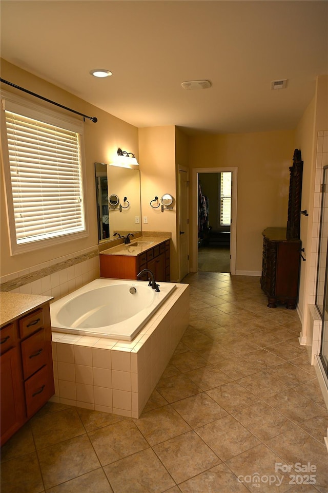 full bathroom with a garden tub, vanity, a shower with shower door, and tile patterned flooring