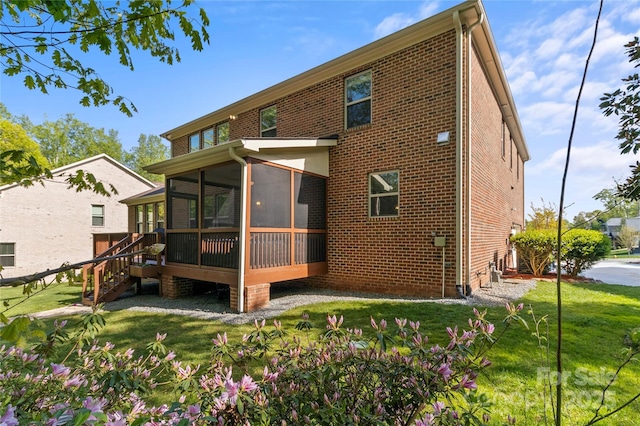 rear view of house featuring a sunroom, a lawn, and brick siding