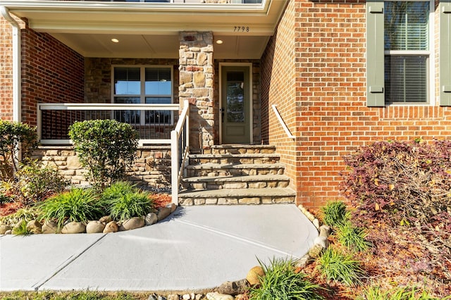 view of exterior entry featuring brick siding and covered porch