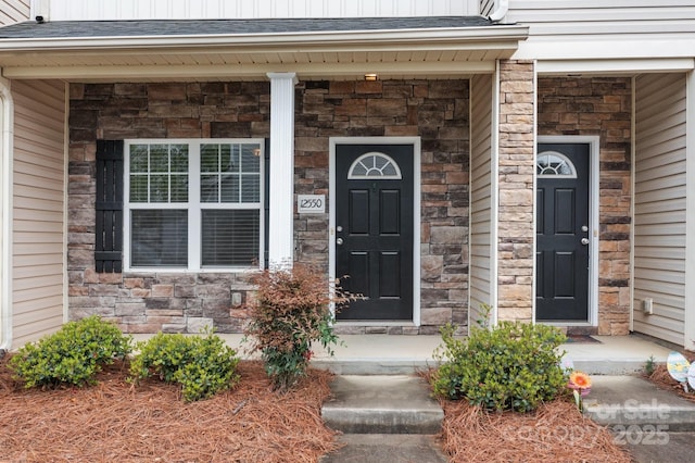 entrance to property featuring covered porch and stone siding