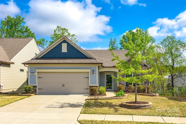 craftsman-style house featuring a front yard, concrete driveway, a shingled roof, and an attached garage