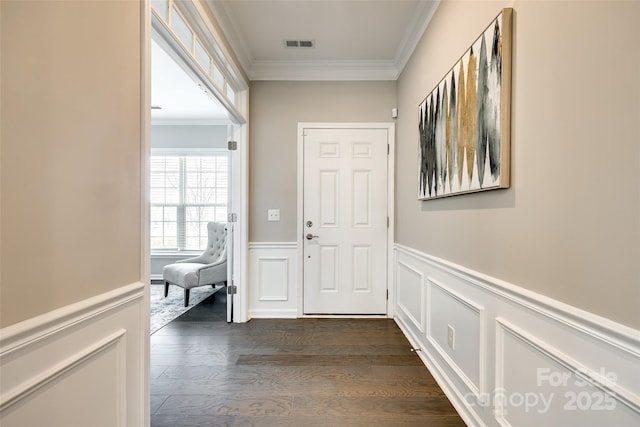 interior space featuring dark wood-type flooring, a wainscoted wall, visible vents, and crown molding