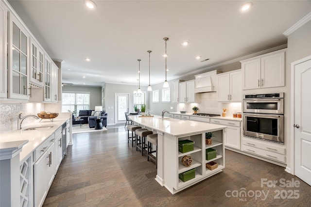 kitchen with stainless steel double oven, a sink, custom exhaust hood, and crown molding